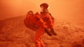 An astronaut on Mars carries a wounded astronaut during a violent dust storm. The man was created using 3D computer
