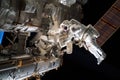astronaut repairing broken equipment on the iss, while other crew members work nearby
