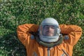 Astronaut sleeping on meadow. Closeup of cosmonaut wearing space suit and helmet taking a nap while lying on green grass Royalty Free Stock Photo