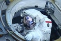 An astronaut in a spacesuit climbs out of the hatch. Elements of this image were furnished by NASA