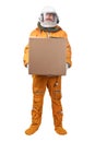 Astronaut wearing orange space suit and space helmet holding in hand blank square cardboard box isolated on white Royalty Free Stock Photo