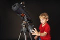 A little boy himself adjusts a large telescope.