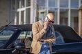 asual mature man using mobile phone and standing next to his car