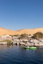 ASWAN, EGYPT - 29 Dec 2022. Vertical beautiful landscape of two Nubian arab men rowing in the Nile river bank with sand