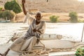 ASWAN, EGYPT 21.05.2018 Old Nubian Man Sitting on Felucca Boat Deck and Sailing Down the Nile River Royalty Free Stock Photo