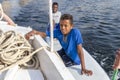 Aswan, Egypt - September 13, 2018: Egyptian children in a surf table hold on to the side of tourist boat in Nile river waiting for