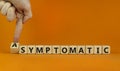 Asymptomatic or symptomatic covid-19. Male hand turns cubes and changes the word `symptomatic` to `asymptomatic`. Beautiful or