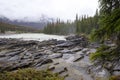 Athabasca Falls in the Rocky Mountains of Canada. Between the cliffs above the water stuck logs. Cloudy day in Jasper Royalty Free Stock Photo