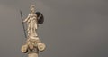 Athena goddess marble statue as a woman warrior with spear, helmet and shield on dark grey sky background