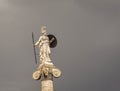 Athena statue, the ancient Greek goddess, as a woman warrior with shield, helmet and spear isolated on a dark grey sky background.