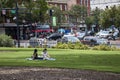 Two women picnic on the grass with a busy view of a bustling downtown district