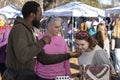 A vendor demonstrates a line of natural bath and body products to customers at an outdoor market