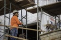 A mason on scaffolding looks over the installation of brick veneer on a new building