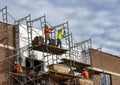 Masons on scaffolding install brick veneer on a new building