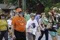 A colorfully dressed smiling senior couple walk hand-in-hand in a parade.