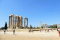 A group of tourists walking around admiring the remains of Temple of Olympian Zeus in Athens, Greece on a beautiful hot summer day
