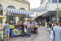 Tourists pass by and buying fruit from street fruit vendor under Athens Flea Market sign in Plaka