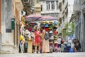 Two women enjoy conversing in front of street vendors hat stand in Plaka area of city