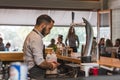 ATHENS, GREECE - SEPTEMBER 17, 2018: Young handsome bartender using smartphone in front of the bar