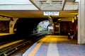 Woman waiting at outdoor covered metro station in early morning with a train approaching