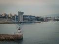 Conseptual shot of the ship that is leaving the port the other ships and the command tower ,in a cloudy day with calm sea Royalty Free Stock Photo