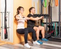 Athete people doing squats leaning on wall in gym