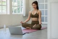 Athlete Asian indian woman looking laptop practice yoga lotus pose online course at home