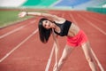 Athlete Attractive sporty brunette woman in pink shorts and top exercise stretching at sport stadium in evening, sunset. Sport and Royalty Free Stock Photo