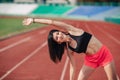 Athlete Attractive sporty brunette woman in pink shorts and top exercise stretching at sport stadium in evening, sunset. Sport and Royalty Free Stock Photo