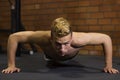 Athlete with a beautiful body and a naked torso doing push-ups exercise on the floor. Studio shot in a dark tone.