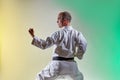 Athlete with a black belt training formal exercises against a colored background with yellow and green tints Royalty Free Stock Photo