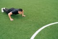 The athlete in black clothes does pushups look ahead in front of him. The concept of social distance outdoors in the park