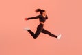 Athlete black woman in sportswear jumping and having workout on red neon studio background, copy space, full length