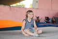 Athlete Caucasian boy sitting on trampoline after training. child is engaged in trampolining on professional trampoline outside. Royalty Free Stock Photo