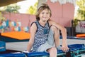 Athlete Caucasian boy sitting on trampoline after training. child is engaged in trampolining on professional trampoline outside. Royalty Free Stock Photo