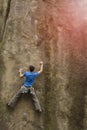 Athlete climbs on rock with rope.