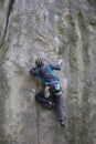 Athlete climbs on rock with rope.