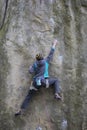 Athlete climbs on rock with rope.