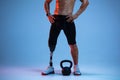 Athlete with disabilities or amputee on blue studio background. Professional male sportsman with leg prosthesis