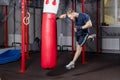 Athlete fighter of mixed martial arts in jump inflicts powerful blow with his hand on punching bag.