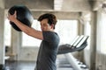 Athlete fit Asian young man swing hard medicine ball at fitness gym Royalty Free Stock Photo