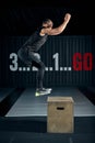 Athlete gave exercise. Jumping on the box. Phase touchdown. Studio shots in the dark tone. Royalty Free Stock Photo