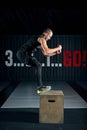 Athlete gave exercise. Jumping on the box. Phase touchdown. Studio shots in the dark tone.