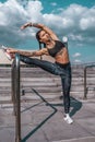 Athlete girl doing stretching in summer in city, practicing yoga. Sportswear leggings top sneakers, woman. The concept