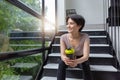 Athlete girll sitting in a black tight-fitting sports suit with a drinking bottle and sitting on the stairs