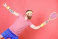 Athlete hipster hold tennis racket in hand red background. Man bearded hipster wear sport outfit. Tennis player beginner Royalty Free Stock Photo