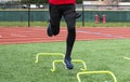 Athlete jumping on one leg over yellow mini banana hurdles