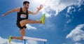 Athlete jumping over hurdles against sky in background Royalty Free Stock Photo