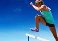 Athlete jumping over hurdles against sky in background Royalty Free Stock Photo