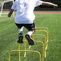 Athlete jumping over yellow hurdles on a green turf field